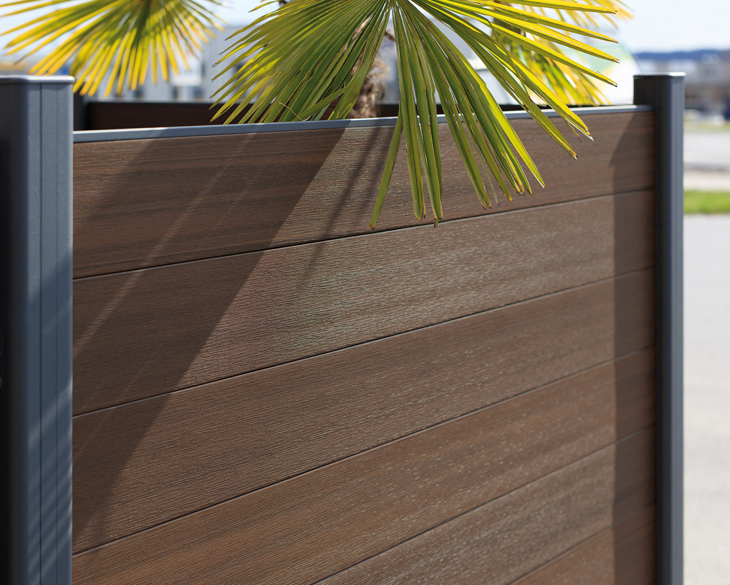 Detailopname van een bruine houtcomposiet schutting met realistische houtnerf textuur en antraciet aluminium palen