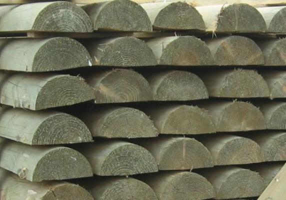 Paardenomheining met halfronde grenen palen en liggers van geïmpregneerd hout in een weide