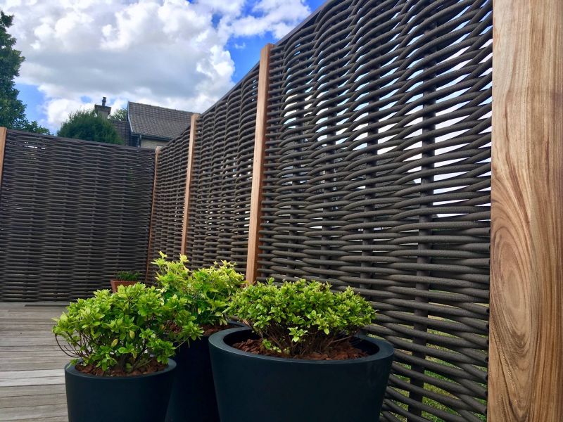Forest Avenue fiber gevlochten tuinscherm in donkerbruin met robuuste houten palen op een dakterras met moderne plantenbakken.