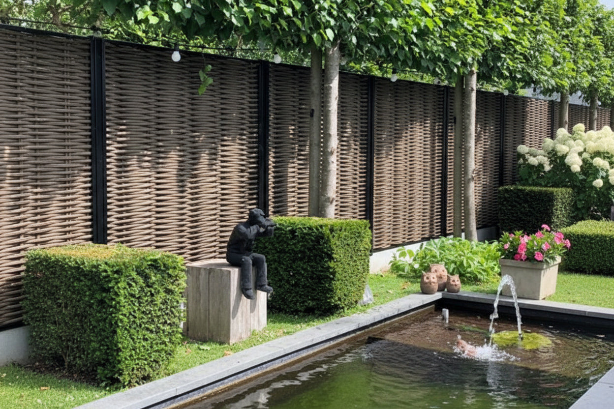 Luxe Forest Avenue fiber gevlochten tuinschermen met zwarte profielen in een moderne tuin met vijver, buxushagen en sfeerverlichting.