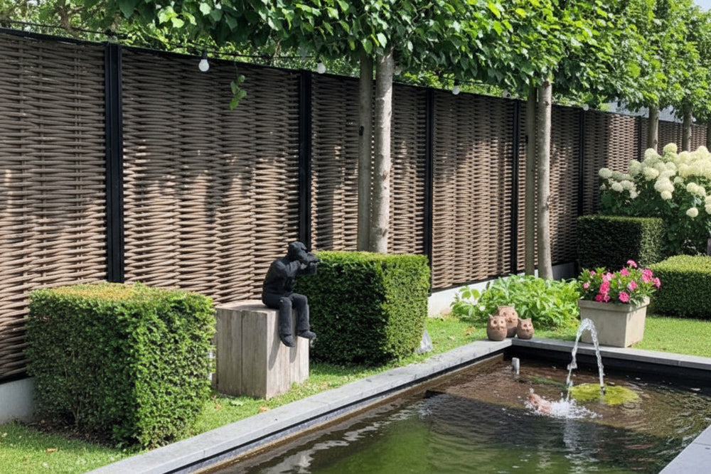 Luxe Forest Avenue fiber gevlochten tuinschermen met zwarte profielen in een moderne tuin met vijver, buxushagen en sfeerverlichting.