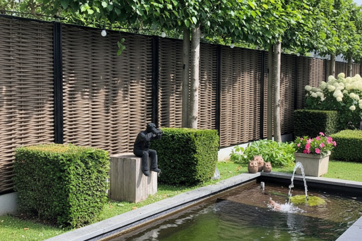 Luxe Forest Avenue fiber gevlochten tuinschermen met zwarte profielen in een moderne tuin met vijver, buxushagen en sfeerverlichting.
